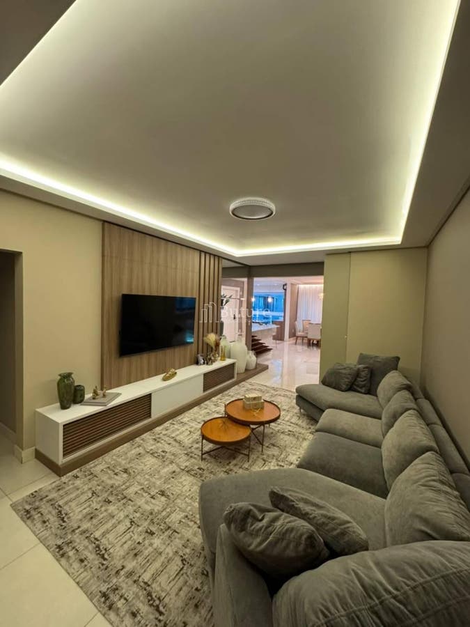 Sala com teto rebaixado, iluminação embutida, decoração moderna e sofá cinza