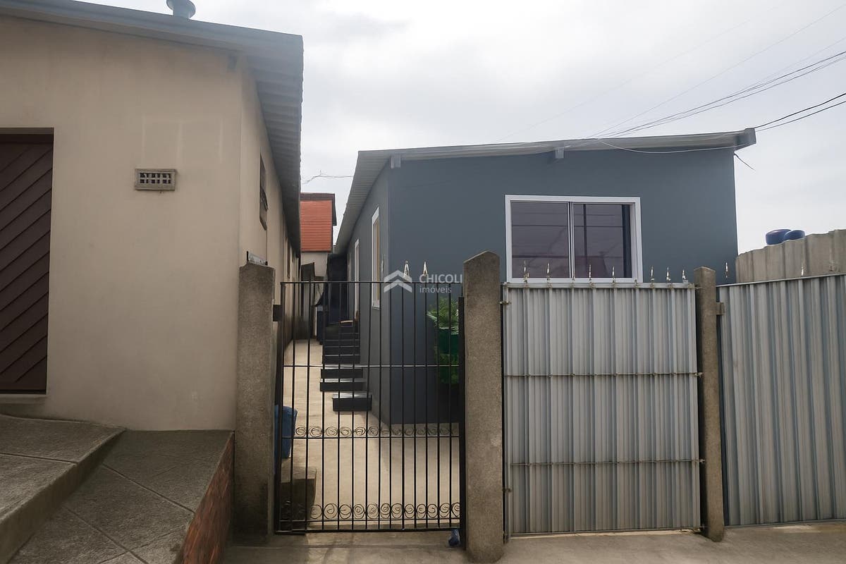 Casa de dois andares com paredes revestidas, cômodo externo com portão de metal. (melhorada por IA)
