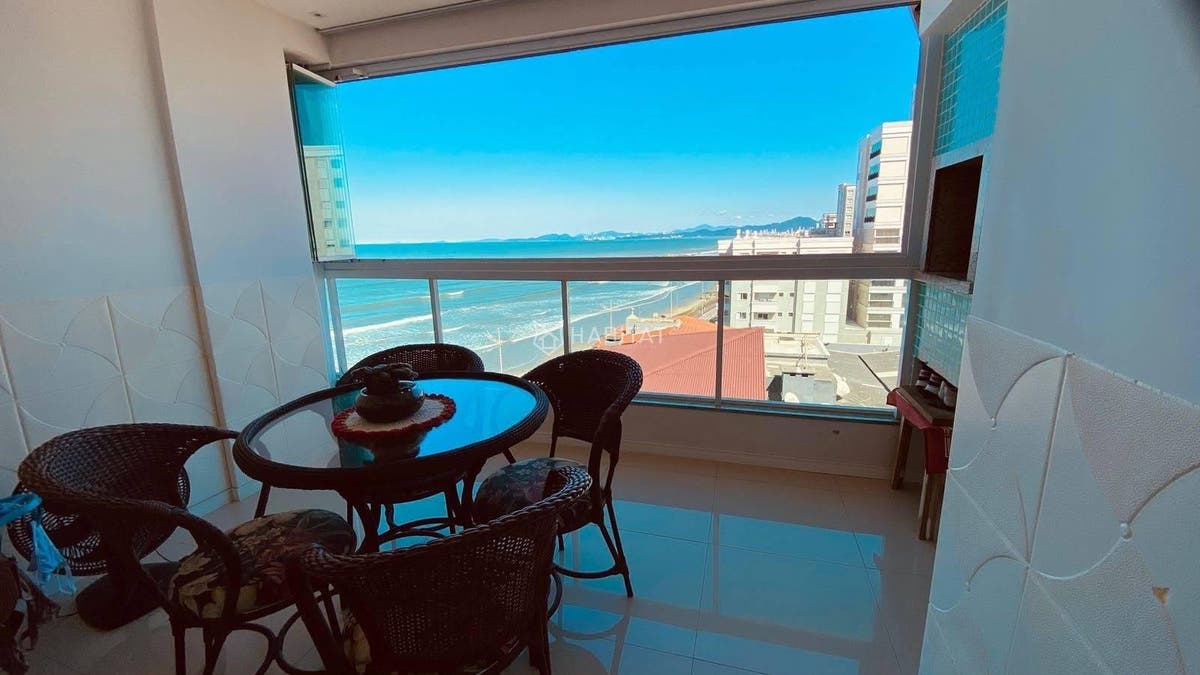 Sala de varanda com vista para o mar, janelas amplas e acabamento branco