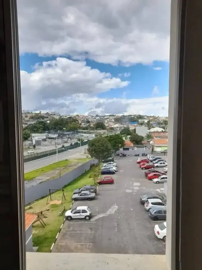 Janela de apartamento com vista para estacionamento e céu nublado