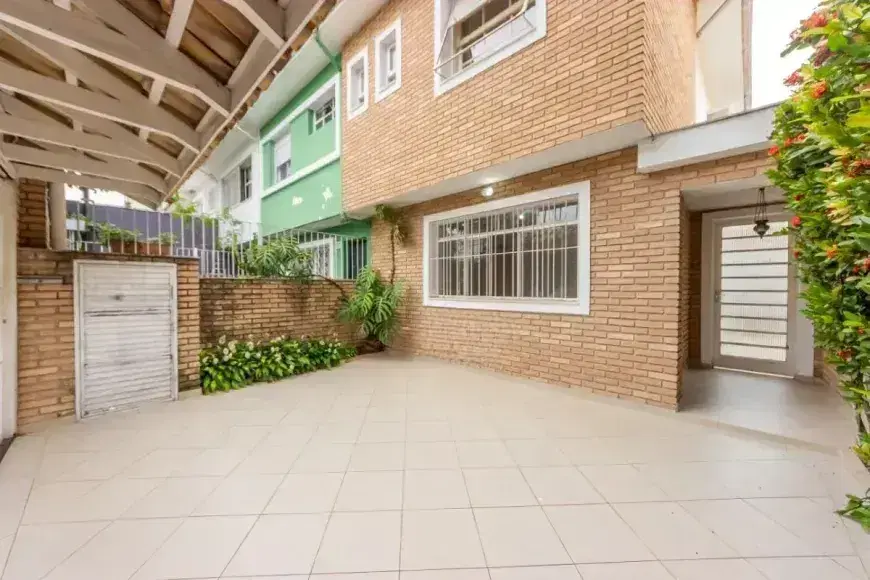 Varanda térrea com piso de azulejos e parede de tijolos expostos