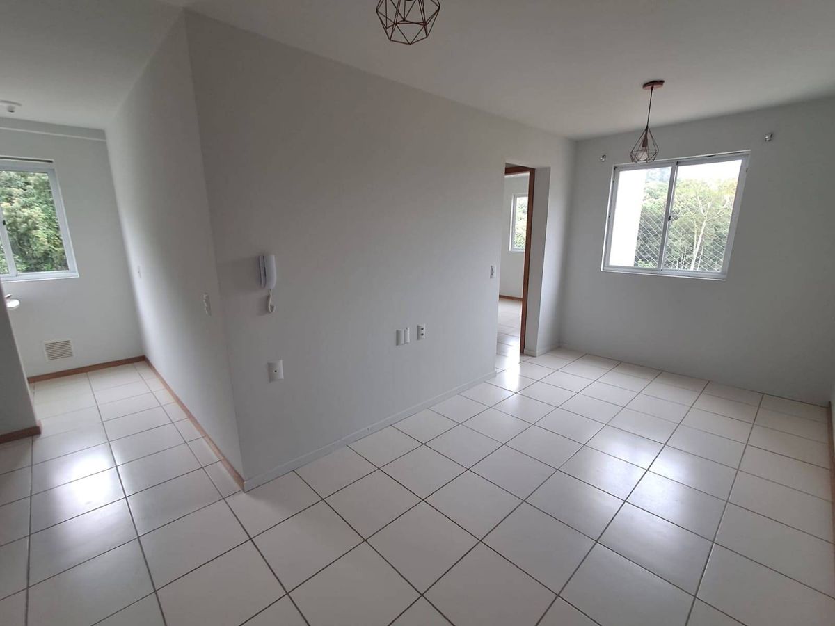 Sala com acabamento em tinta branca, piso de porcelanato, janelas grandes