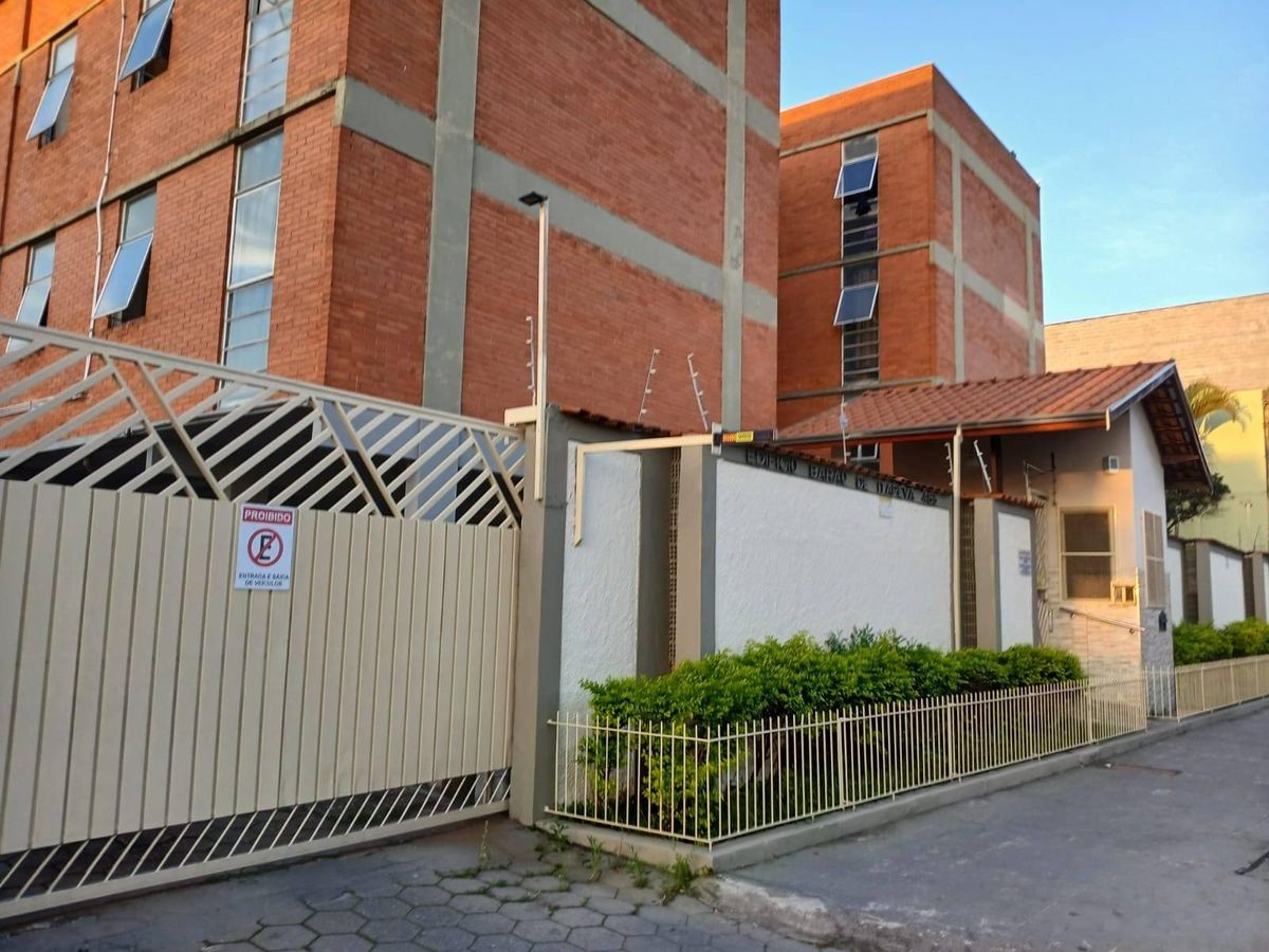 Fachada de prédio com muro de grade, veredas e construção de tijolos.