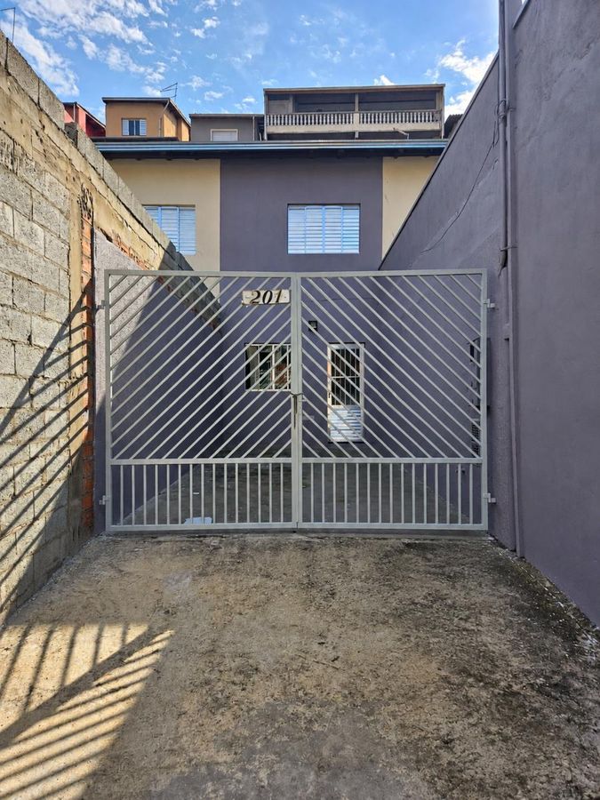 Fachada de residência com muro de blocos e portão de metal branco.