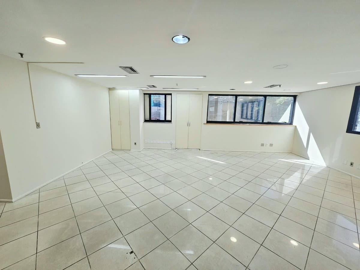 Sala com paredes brancas, janelas grandes e piso de porcelanato claro