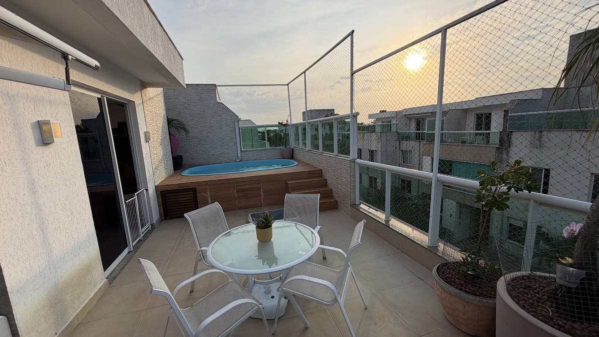 varanda com mesa, cadeiras, piscina, plantas e vista ao entardecer
