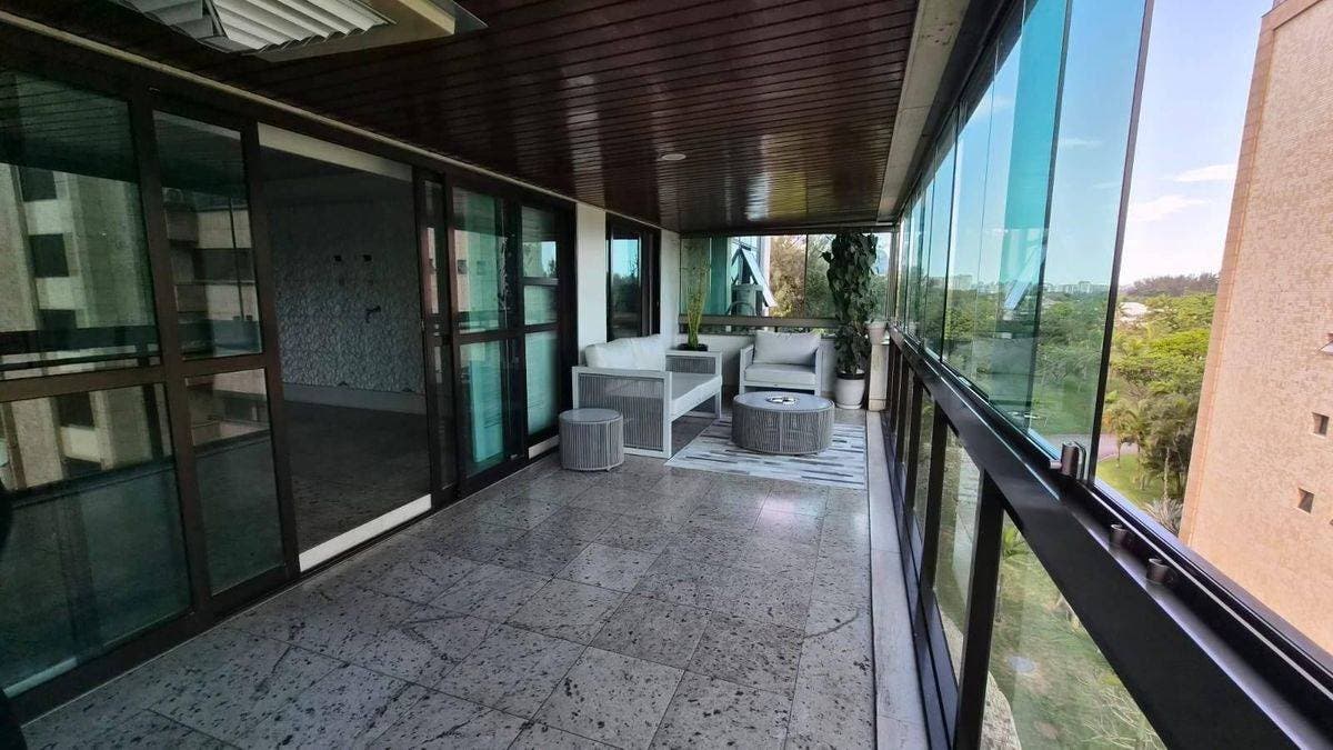 Varanda com piso de granito, móveis brancos e vista para a natureza