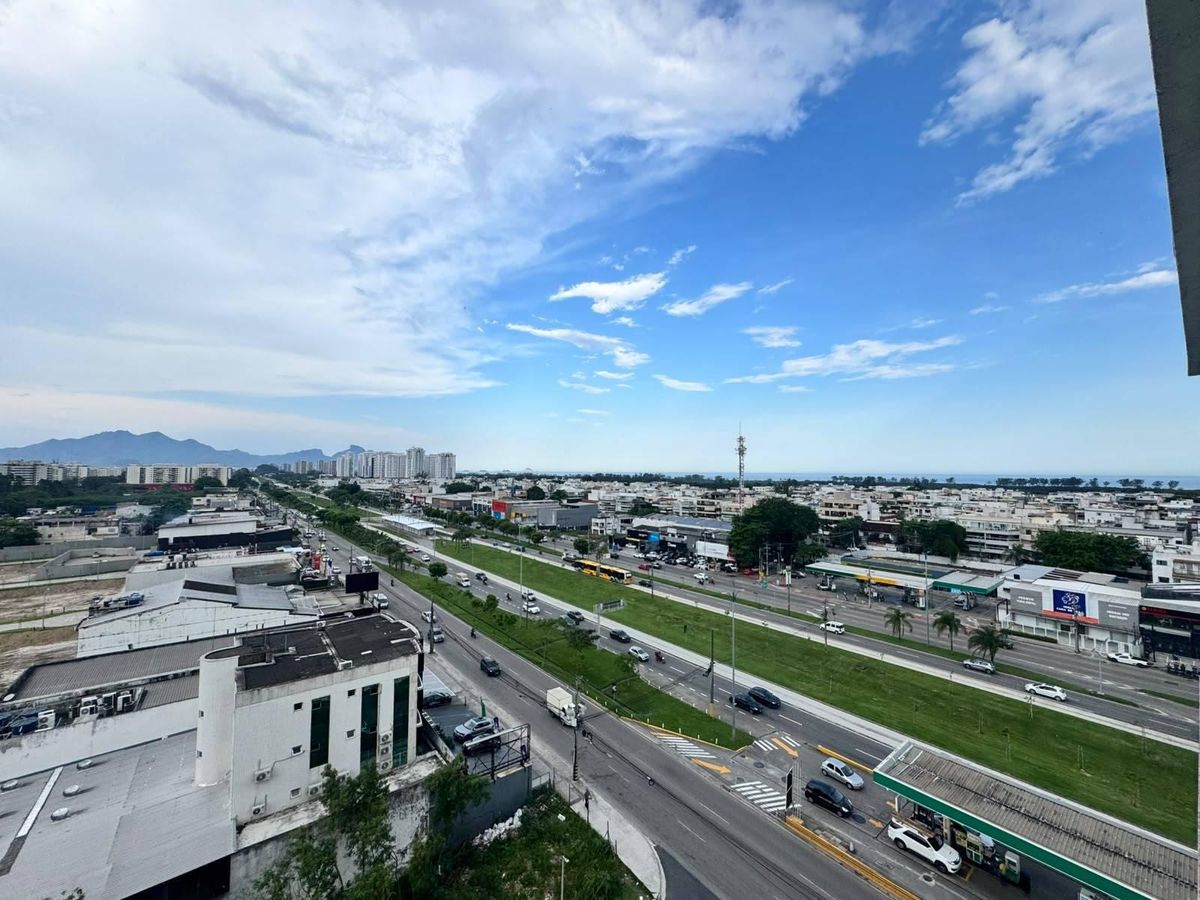 Visão de rua movimentada com prédios, árvores e céu parcialmente nublado.