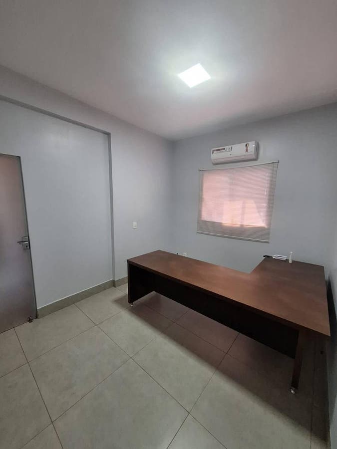 quarto com paredes brancas, piso de porcelanato, janela com cortina, mesa de madeira