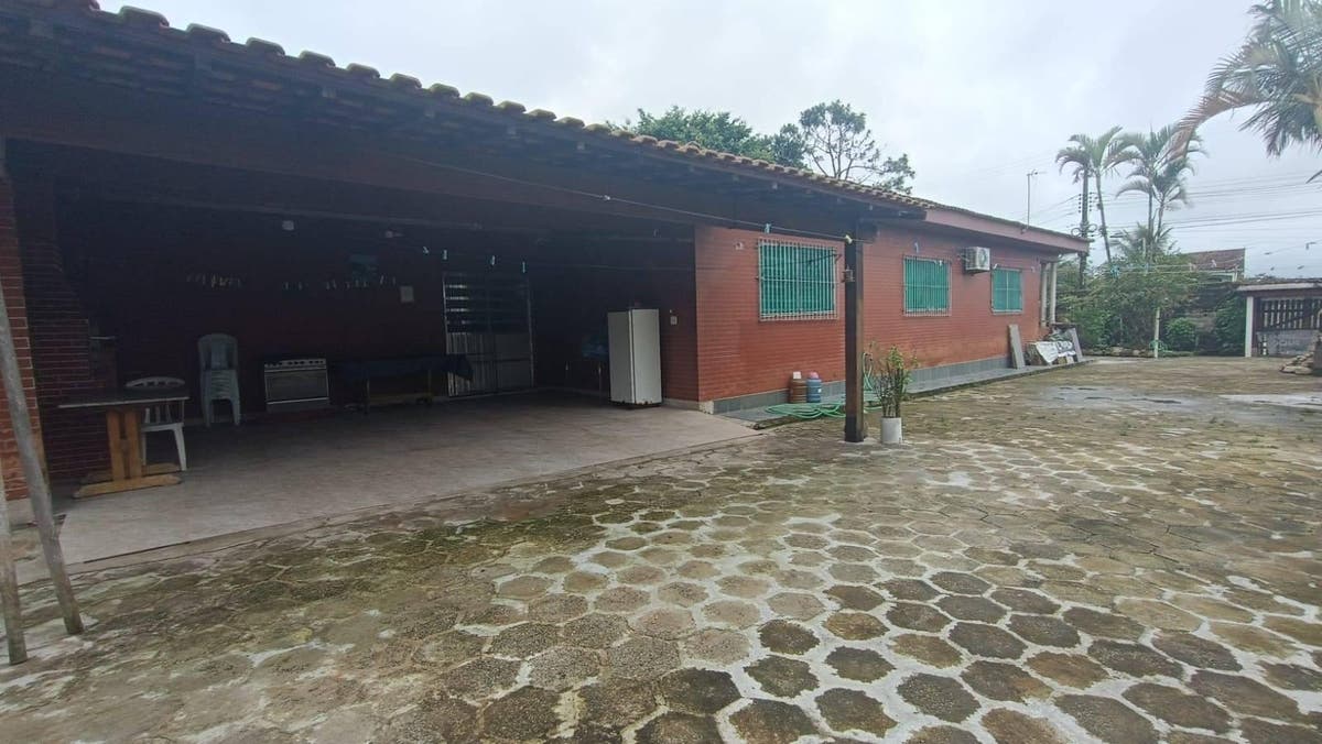 Casa de alvenaria com varanda coberta e espaço externo com piso de pedra
