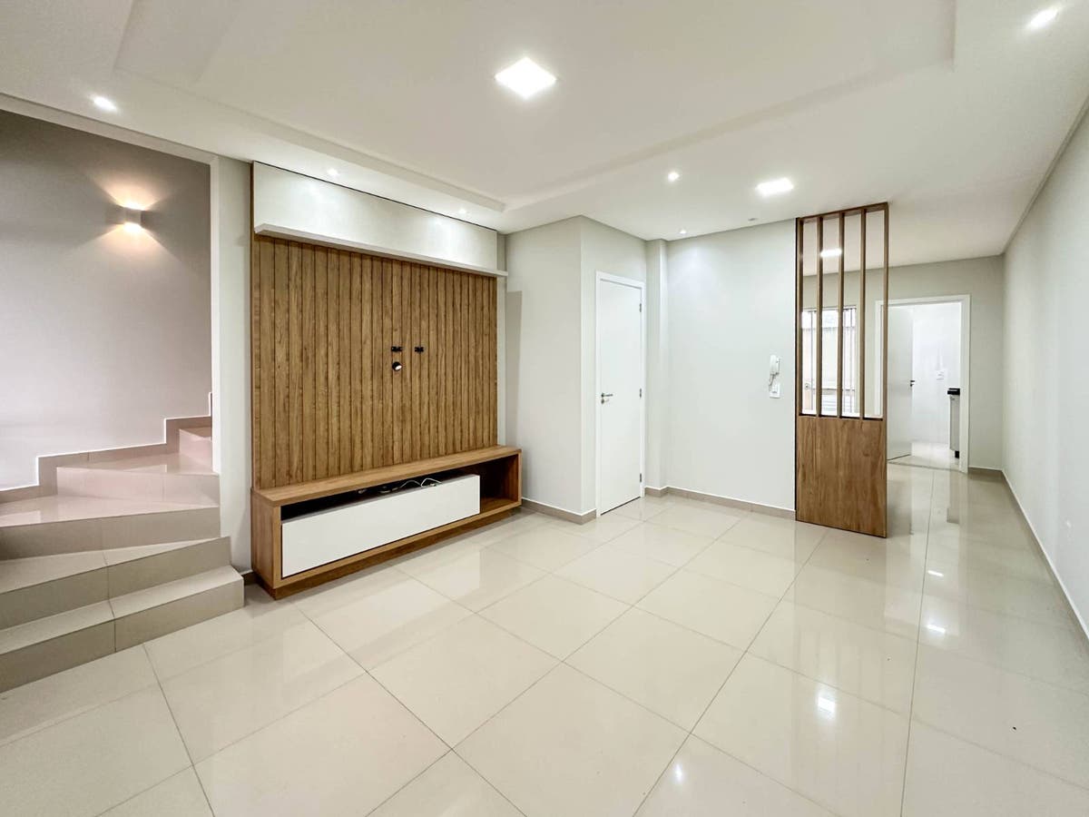 Sala com piso de porcelanato, paredes brancas e teto rebaixado com iluminação embutida