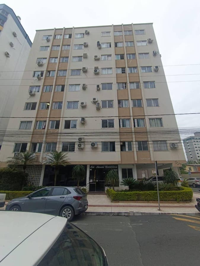 Prédio residencial com janelas e ar-condicionados na fachada.