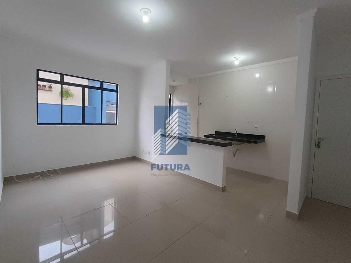 Sala integrada com cozinha, paredes brancas, piso porcelanato, iluminação artificial.