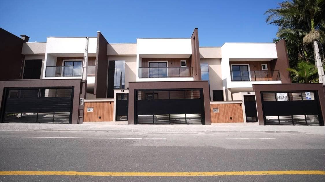 Fachada de prédio residencial moderna com garagem e varanda, dia claro.