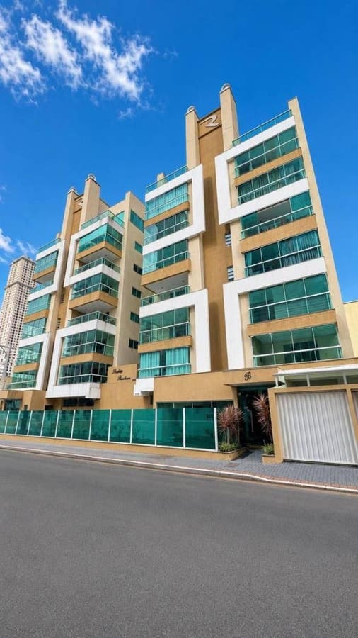 Prédio residencial com vidro e detalhes em bege sob céu azul