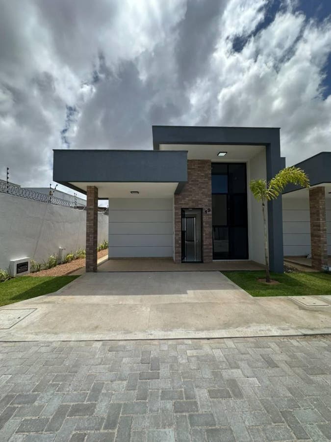 Fachada moderna de casa com garagem, parede de tijolos e céu nublado
