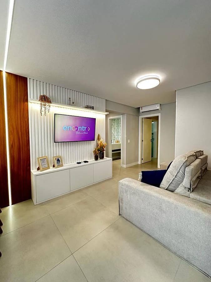 Sala com paredes de revestimento branco e painel para TV