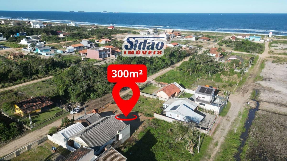 Visão aérea de bairro com casas, vegetação e mar ao fundo