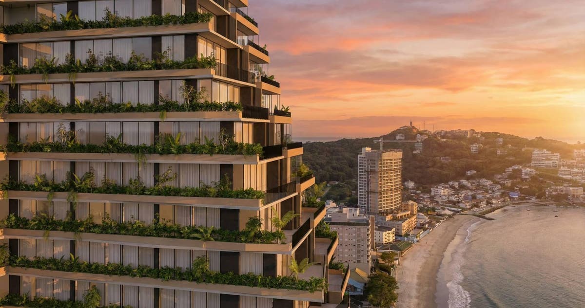 Edifício moderno com varandas verdes, vista para o mar ao pôr do sol