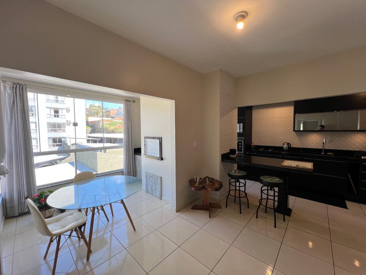 Sala de jantar com varanda, janelas amplas e acabamento em branco.