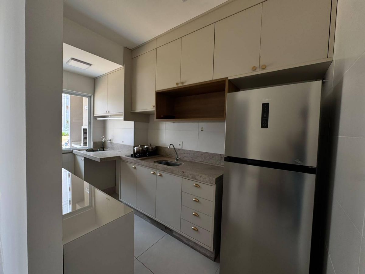 Cozinha moderna com armários claros, bancada de granito, janela e eletrodomésticos.