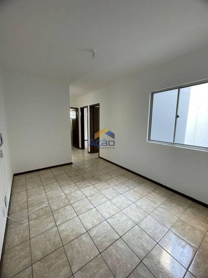 Sala com paredes brancas, janela de vidro, piso de cerâmica, portas de madeira