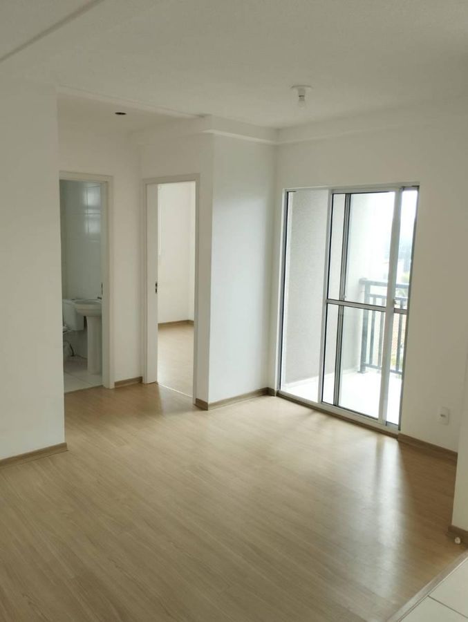 Sala com piso de madeira, parede branca, varanda fechada de vidro.