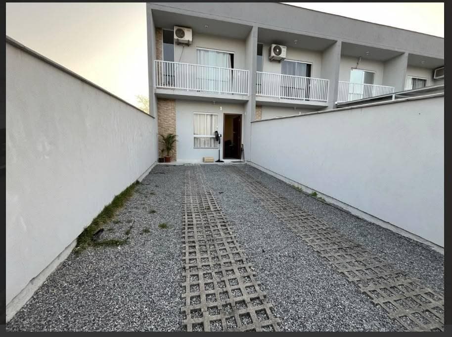 Garagem com parede branca, entrada de piso de blocos de concreto.