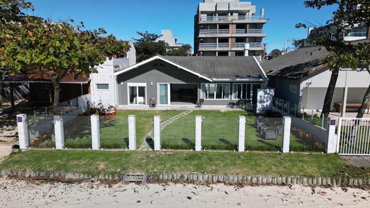 Casa de dois pavimentos, janela de vidro, jardim em frente, cerca de metal.