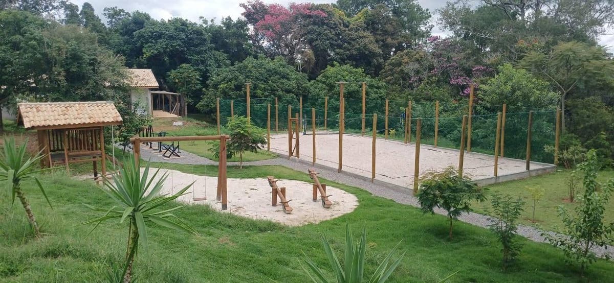 Área de lazer ao ar livre com gramado, árvores e estrutura de futebol