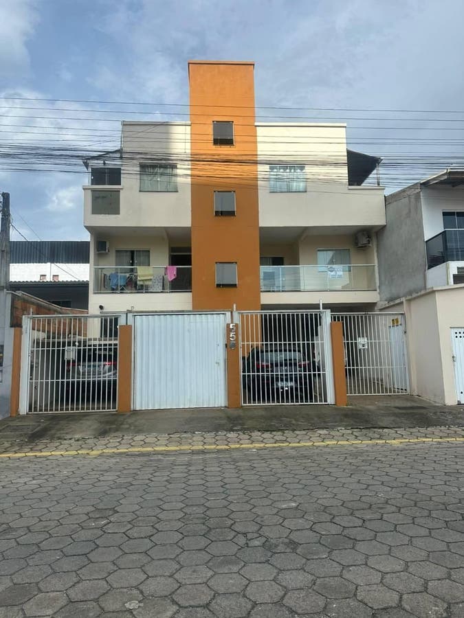 Prédio residencial de estrutura moderna com garagem e varanda.