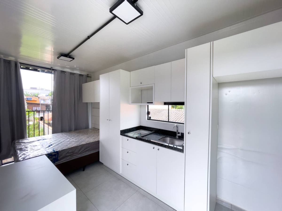 Ambiente interno com cozinha branca e janela, cômodo com teto branco.