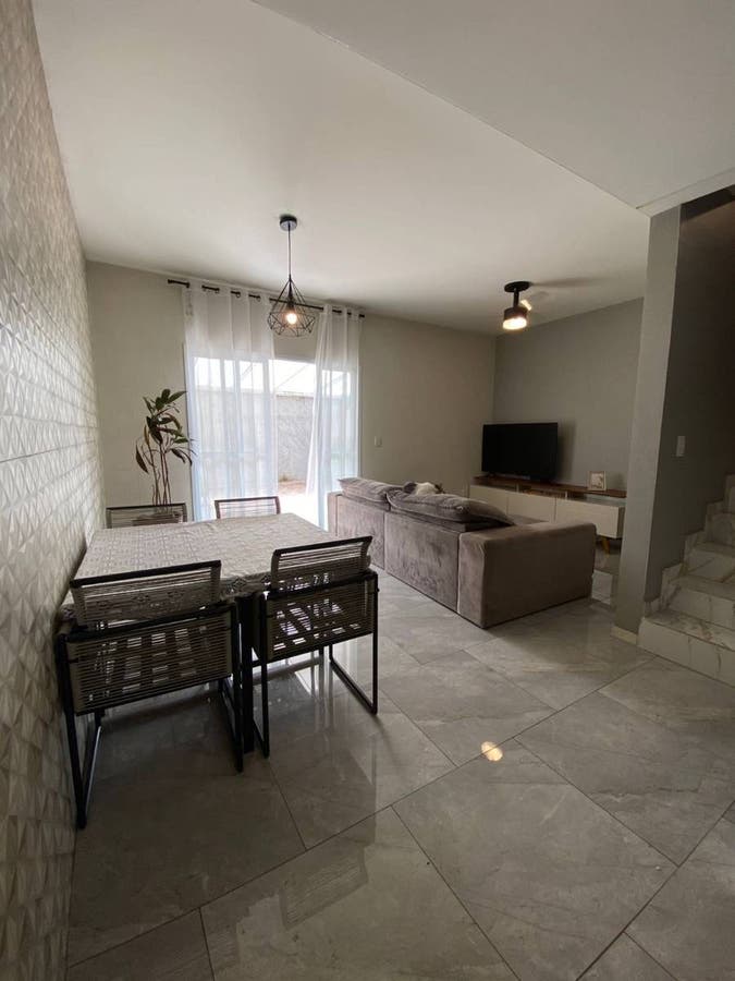 Sala de estar com sofá, TV e cortinas de tecido branco