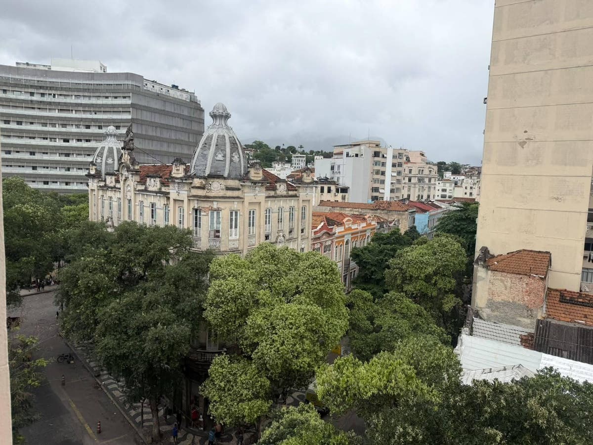 Vista de rua arborizada com edifícios históricos e modernos sob céu nublado