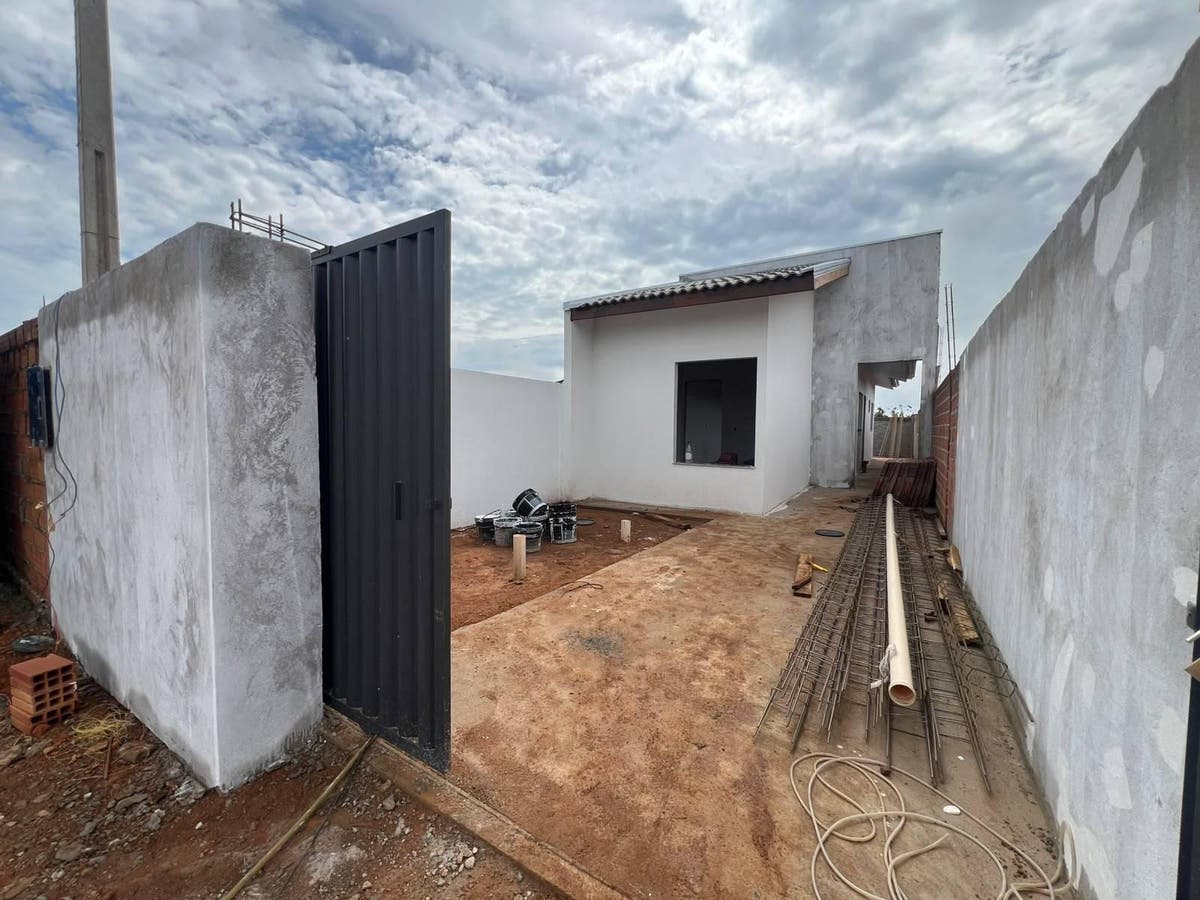 Pátio externo em construção com paredes brancas e chão de terra batida