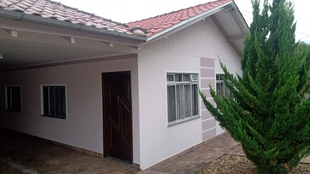 Casa com acabamento em reboco branco e telhado de cerâmica.