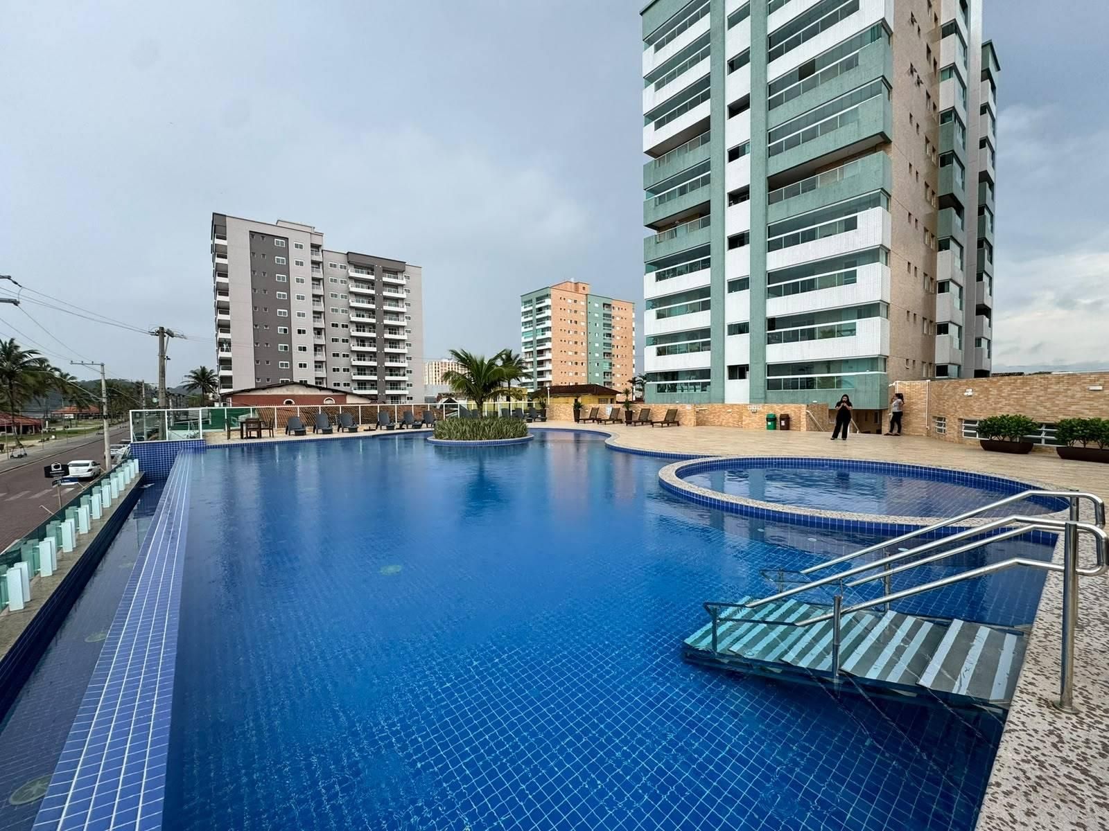 Piscina de prédio com área de descanso ao redor e edifícios no fundo