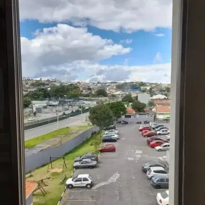 Janela de apartamento com vista para estacionamento e céu nublado