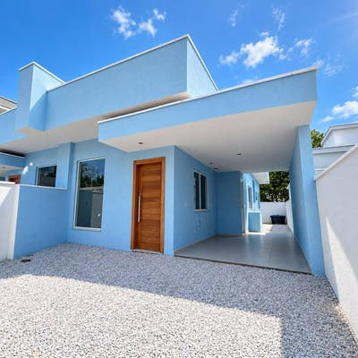 Fachada de casa moderna azul com porta de madeira e muro branco
