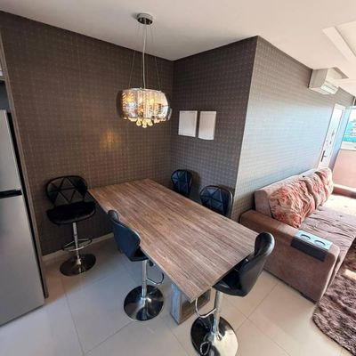 Sala de jantar e estar com móveis, parede de papel de parede escuro.