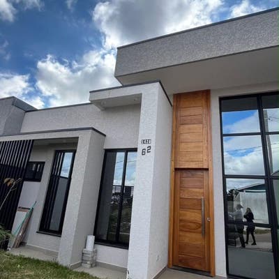 Residência moderna com paredes brancas, janela de vidro e porta de madeira.