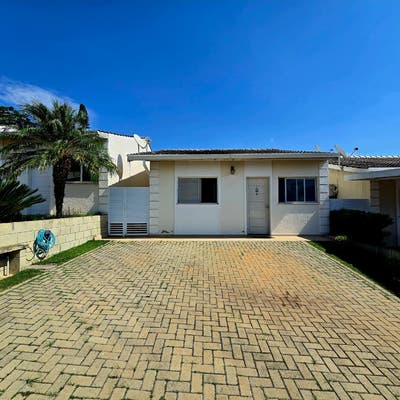 Fachada de casa com jardim frontal, telhado de telhas, paredes brancas.