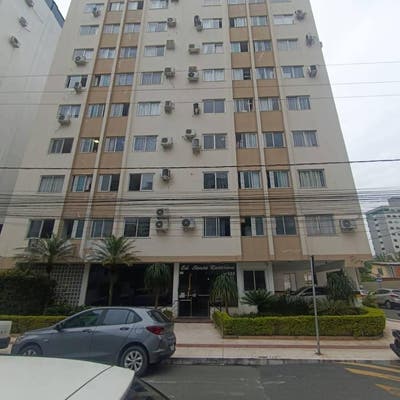 Prédio residencial de altura com janelas e unidades de ar condicionado.