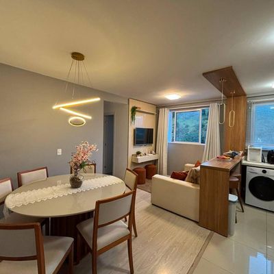 Sala integrada com cozinha, iluminação artificial, janelas com cortinas brancas