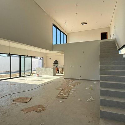Sala ampla com janelas de vidro até o teto e acabamento em concreto