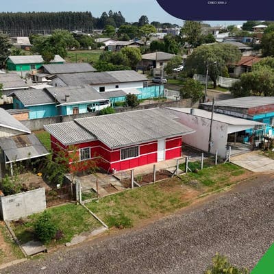 Rua com casas de telhado de duas águas, árvores e calçamento de pedra.