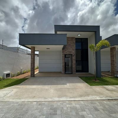 Fachada moderna de casa com garagem, parede de tijolos e céu nublado