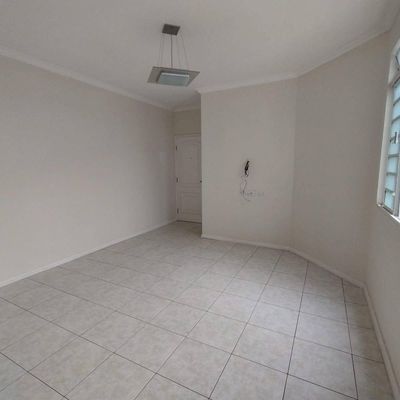 Sala vazia com paredes claras, janela de vidro, piso de cerâmica.
