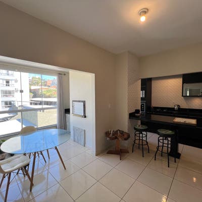 Sala de jantar com varanda, janelas amplas e acabamento em branco.