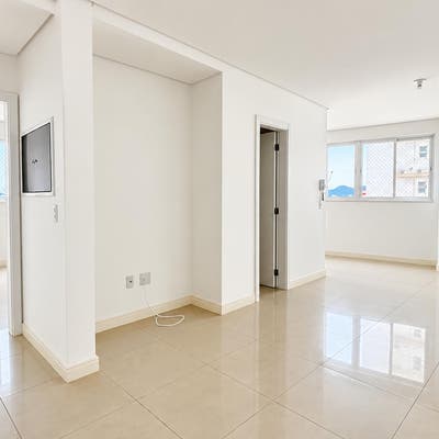 Sala de estar com paredes brancas, janelas grandes e piso de porcelanato.